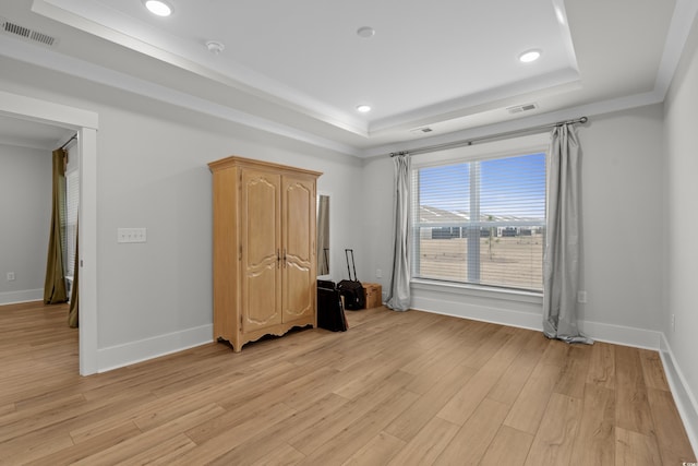 unfurnished bedroom with a raised ceiling and light hardwood / wood-style flooring