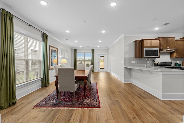 dining space featuring sink, crown molding, a wealth of natural light, and light wood-type flooring