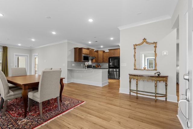 dining area featuring ornamental molding, sink, and light wood-type flooring