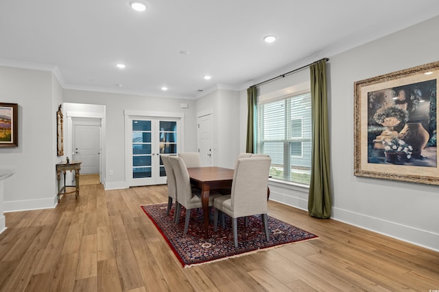 dining room with crown molding, light wood-type flooring, and french doors