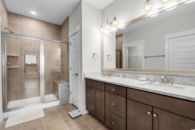 bathroom with a shower with door, vanity, and tile patterned flooring