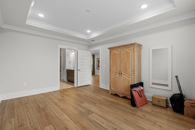 unfurnished bedroom featuring connected bathroom, a raised ceiling, and light hardwood / wood-style flooring