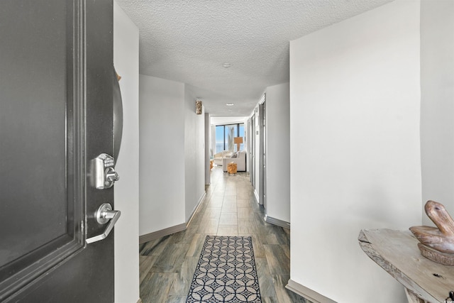 hallway with a textured ceiling and dark hardwood / wood-style flooring