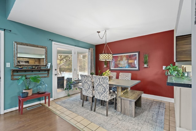 tiled dining area with french doors, visible vents, baseboards, and a barn door