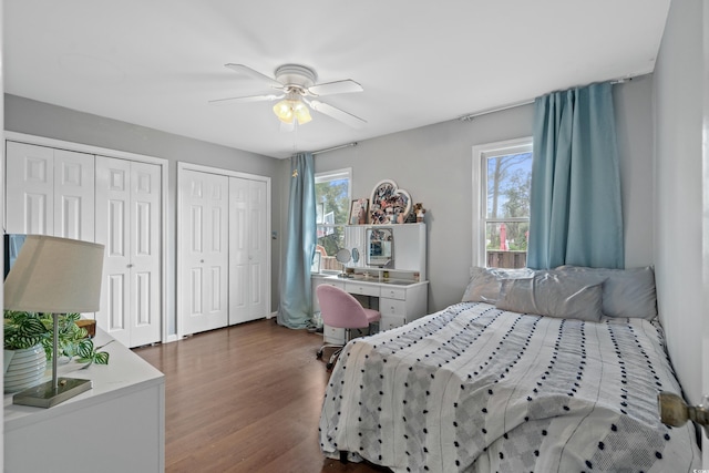 bedroom with multiple closets, multiple windows, dark wood finished floors, and ceiling fan