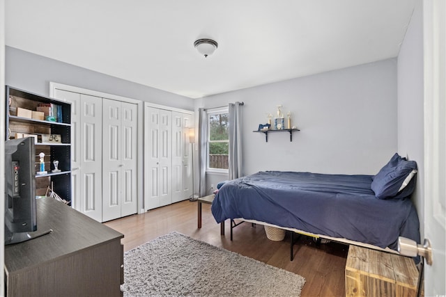 bedroom with two closets and wood finished floors