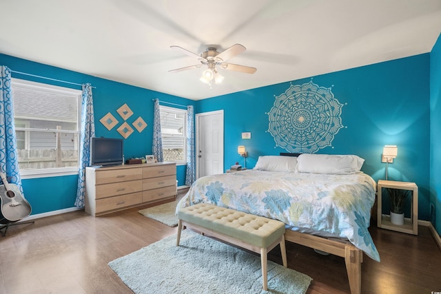 bedroom with a ceiling fan, baseboards, and wood finished floors