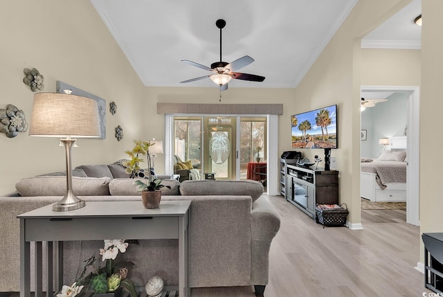 living room featuring crown molding, vaulted ceiling, ceiling fan, and light wood-type flooring