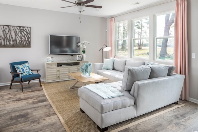 living area featuring wood finished floors, a ceiling fan, and baseboards