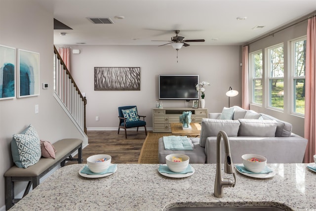 living room with ceiling fan, wood finished floors, baseboards, and stairway