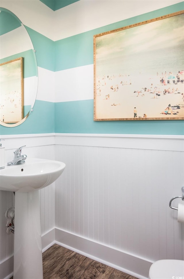 half bathroom with a wainscoted wall and wood finished floors