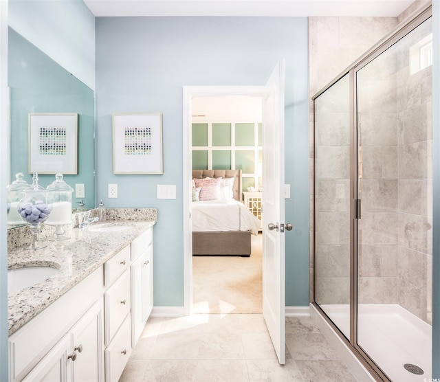 bathroom with a shower stall, ensuite bathroom, baseboards, and double vanity