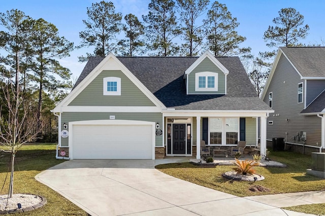 craftsman-style house with cooling unit, a garage, covered porch, and a front lawn