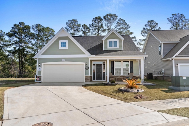 view of front of home with a porch, a garage, central AC unit, and a front lawn