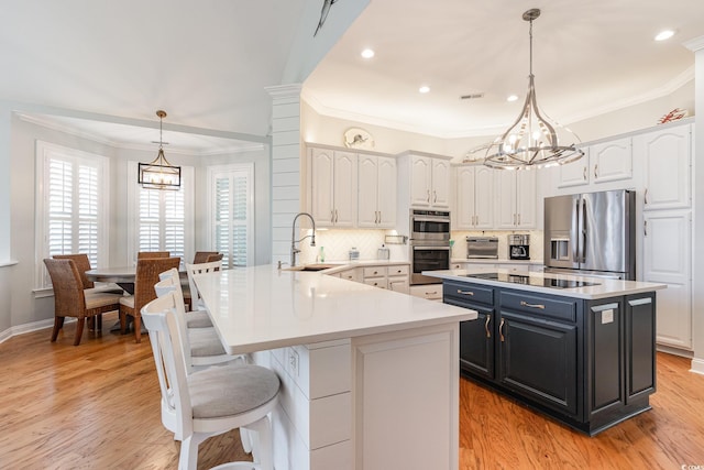 kitchen featuring white cabinetry, appliances with stainless steel finishes, sink, and decorative light fixtures