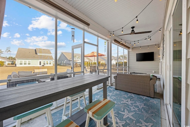 sunroom / solarium featuring ceiling fan and track lighting