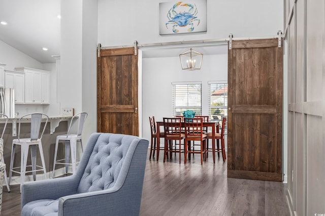 dining room featuring a high ceiling, a barn door, and dark wood-type flooring