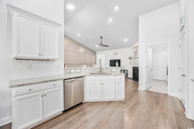 kitchen with sink, stainless steel dishwasher, white cabinets, and light stone counters