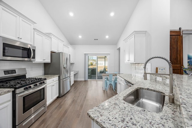 kitchen featuring white cabinetry, sink, stainless steel appliances, and light stone countertops