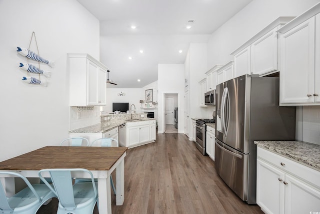 kitchen with stainless steel appliances, kitchen peninsula, and white cabinets