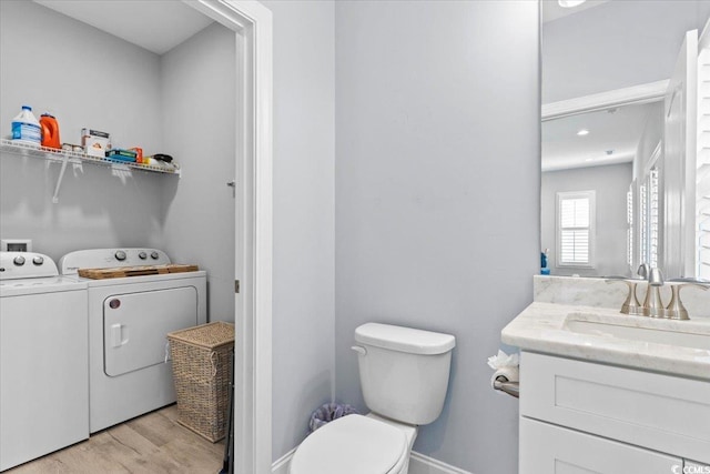 bathroom with vanity, wood-type flooring, washer and dryer, and toilet