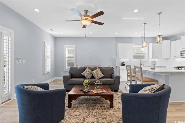 living room featuring sink, ceiling fan, and light hardwood / wood-style flooring