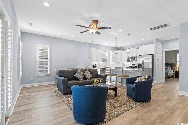 living room featuring ceiling fan and light hardwood / wood-style flooring