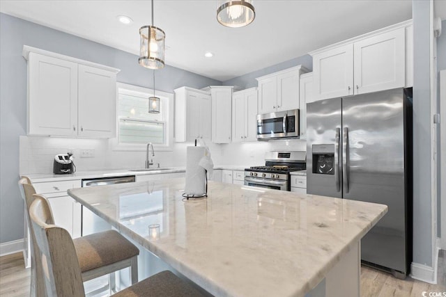 kitchen with pendant lighting, white cabinetry, a center island, and appliances with stainless steel finishes