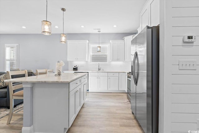 kitchen featuring a kitchen bar, hanging light fixtures, appliances with stainless steel finishes, a kitchen island, and white cabinets