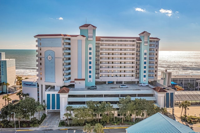 view of building exterior featuring a water view and a beach view