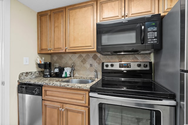 kitchen featuring appliances with stainless steel finishes, light stone countertops, sink, and decorative backsplash