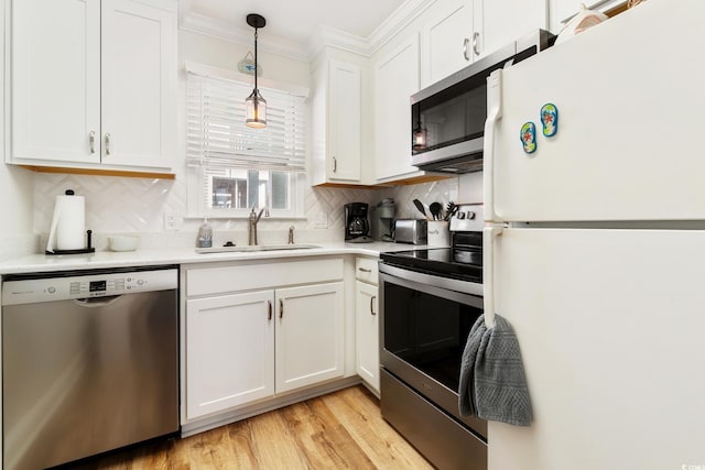 kitchen featuring sink, hanging light fixtures, stainless steel appliances, tasteful backsplash, and white cabinets