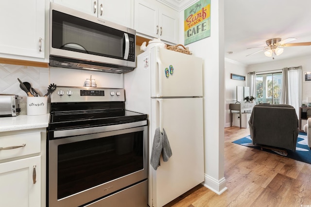 kitchen featuring appliances with stainless steel finishes, tasteful backsplash, white cabinets, ceiling fan, and light hardwood / wood-style floors