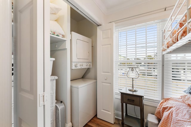 laundry area with hardwood / wood-style flooring, crown molding, and stacked washer / drying machine