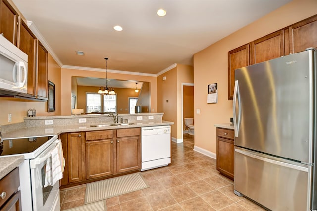 kitchen with pendant lighting, white appliances, kitchen peninsula, and sink