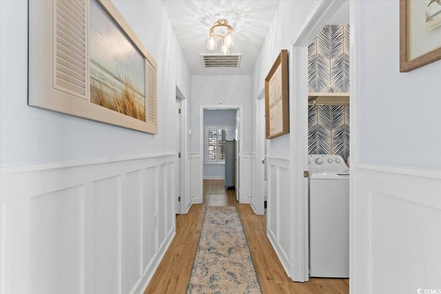 hallway with washer / clothes dryer and light hardwood / wood-style floors