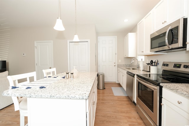 kitchen with sink, appliances with stainless steel finishes, white cabinetry, a kitchen breakfast bar, and a kitchen island