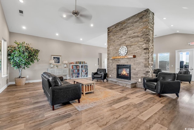 living room with high vaulted ceiling, a stone fireplace, light hardwood / wood-style floors, and ceiling fan