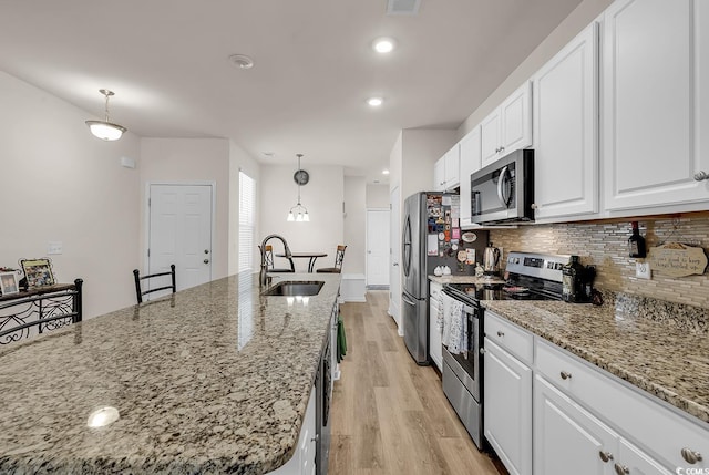 kitchen featuring white cabinetry, stainless steel appliances, decorative light fixtures, and sink