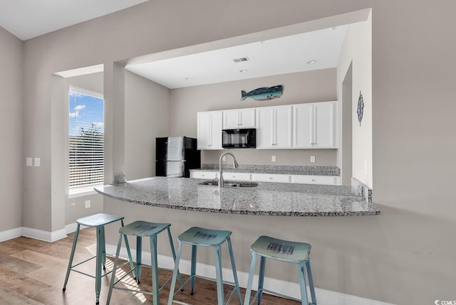 801 San Marco Ct Unit C, Myrtle Beach, SC 29579 - kitchen featuring black appliances, a sink, white cabinetry, light stone countertops, and a breakfast bar area