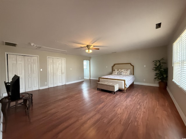 unfurnished bedroom featuring ceiling fan, two closets, and dark hardwood / wood-style flooring