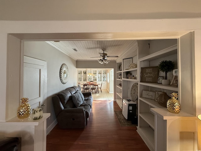 living area with crown molding, dark wood-type flooring, and ceiling fan