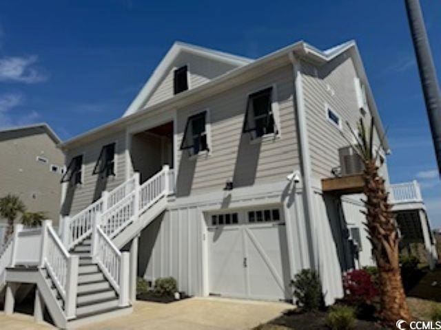 view of front facade featuring driveway, covered porch, stairway, board and batten siding, and a garage