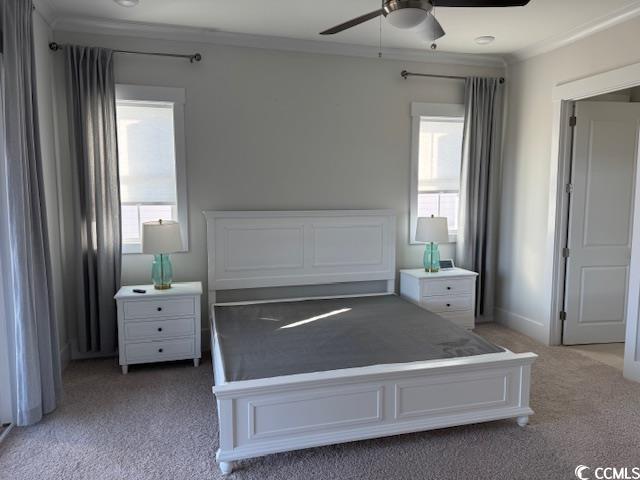 unfurnished bedroom featuring ceiling fan, ornamental molding, and light carpet