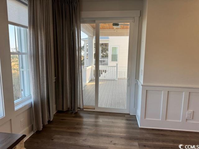 interior space with a decorative wall, dark wood-style flooring, and a wainscoted wall