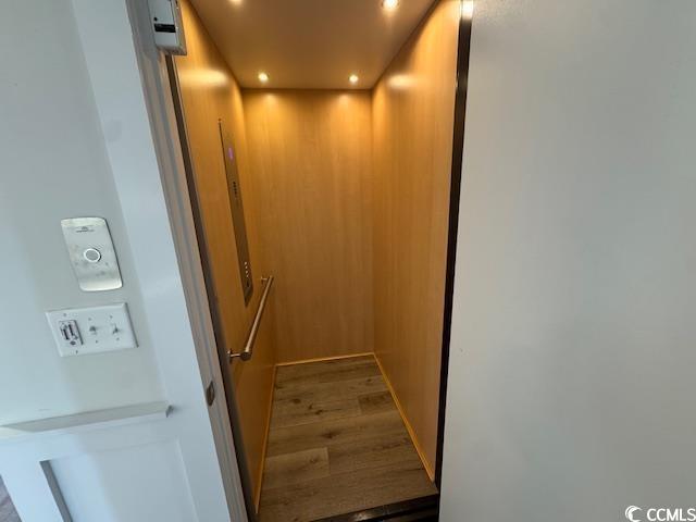 room details featuring elevator, wood finished floors, and recessed lighting