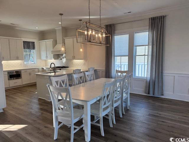 dining area featuring dark wood-style floors, a notable chandelier, and ornamental molding