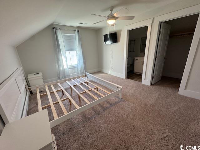 unfurnished bedroom with a ceiling fan, a spacious closet, lofted ceiling, baseboards, and carpet