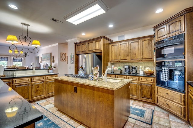 kitchen featuring stainless steel refrigerator, decorative light fixtures, tasteful backsplash, an island with sink, and sink