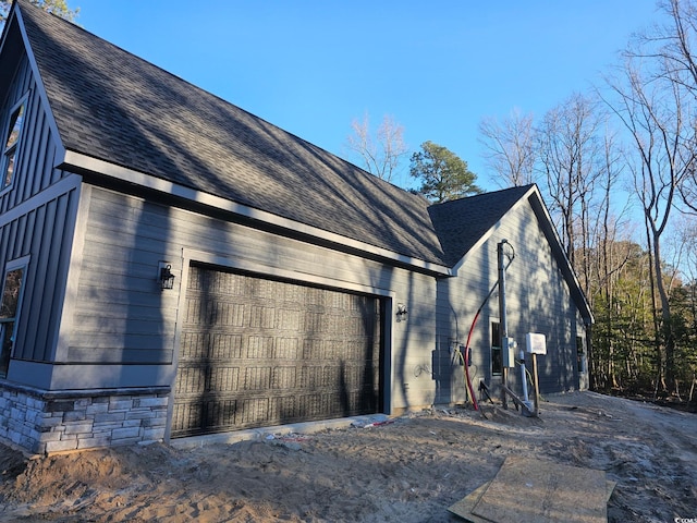 view of property exterior with a detached garage and roof with shingles